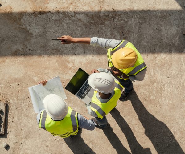 Top view, Team engineer building inspection use tablet computer and blueprint working at construction site. Civil Engineer, Contractor and Architect discussing in construction site.